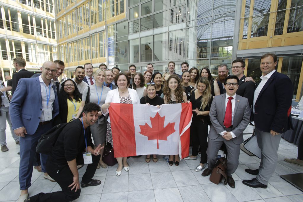 Kelly at the G20 Young Entrepreneurs' Alliance summit standing with a group of delegates holding the Canadian flag